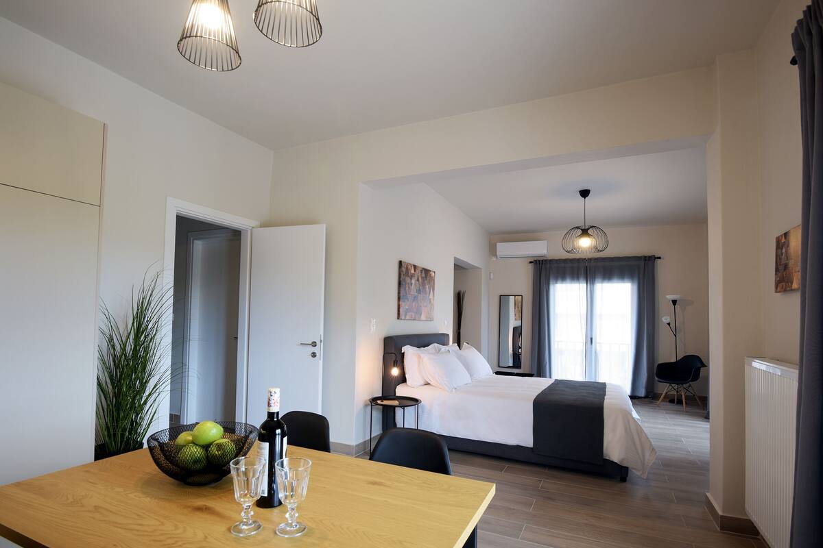 A hotel room with a bed, bedside table, and a dining area with a table and chairs.