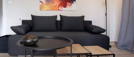 Un salon moderne avec un canapé gris foncé, une table basse ronde et un lampadaire.