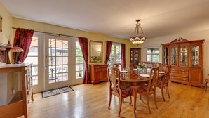 A spacious dining room with a wooden table and chairs, a chandelier, and a large wooden cabinet. - Southern California Vacation Rental: Private Pool! (Ontario)
