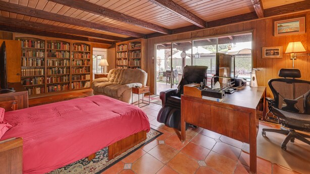 A cozy room with a large bed, a desk, a chair, and a bookshelf. - Southern California Vacation Rental: Private Pool! (Ontario)