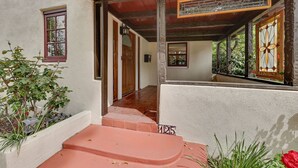 A staircase leading to a door with a number plate '125' and a view of a covered outdoor area with plants. - Southern California Vacation Rental: Private Pool! (Ontario)