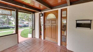 A covered porch with a wooden ceiling, a tiled floor, and a door with a glass panel. - Southern California Vacation Rental: Private Pool! (Ontario)