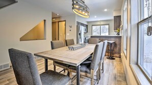A dining area with a wooden table and chairs, a hanging light fixture, and a view of the kitchen and living area through a large window. - 8 Mi to Copper Mtn: Sleek Frisco Townhome w/ Views (Frisco)