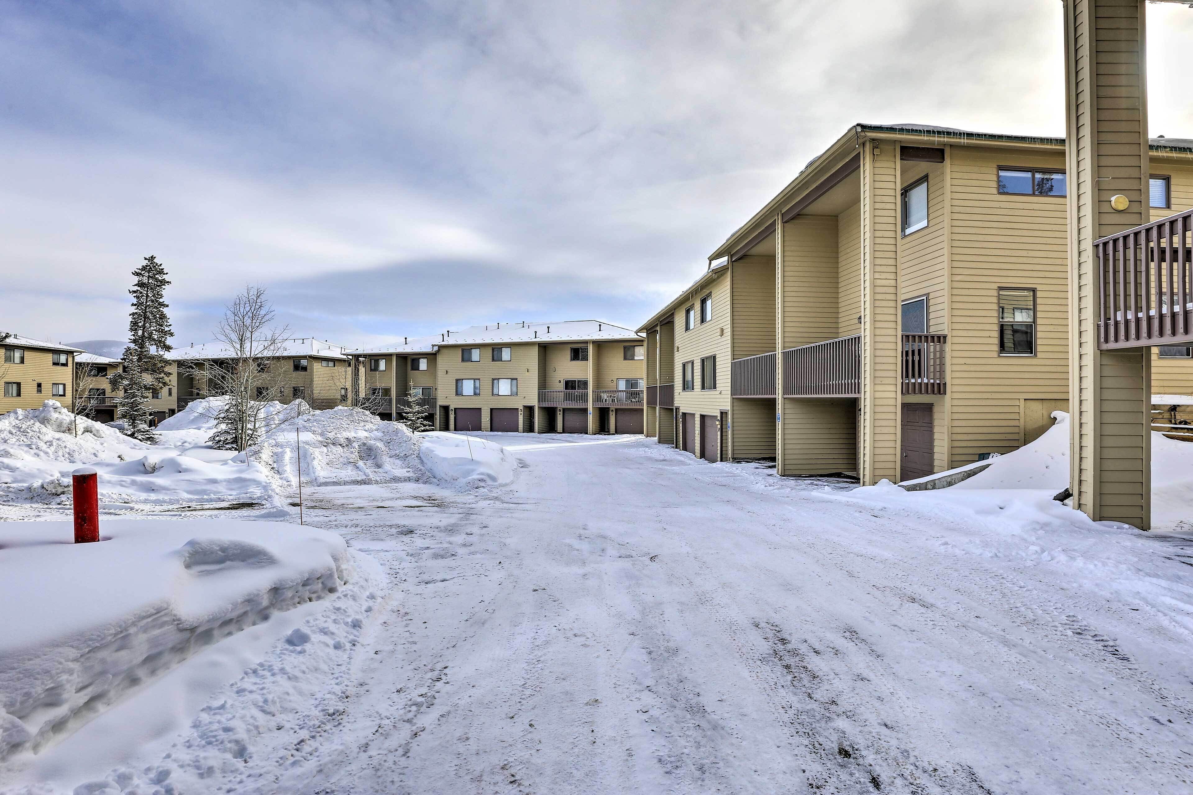 A snow-covered road in a residential area with apartment buildings.