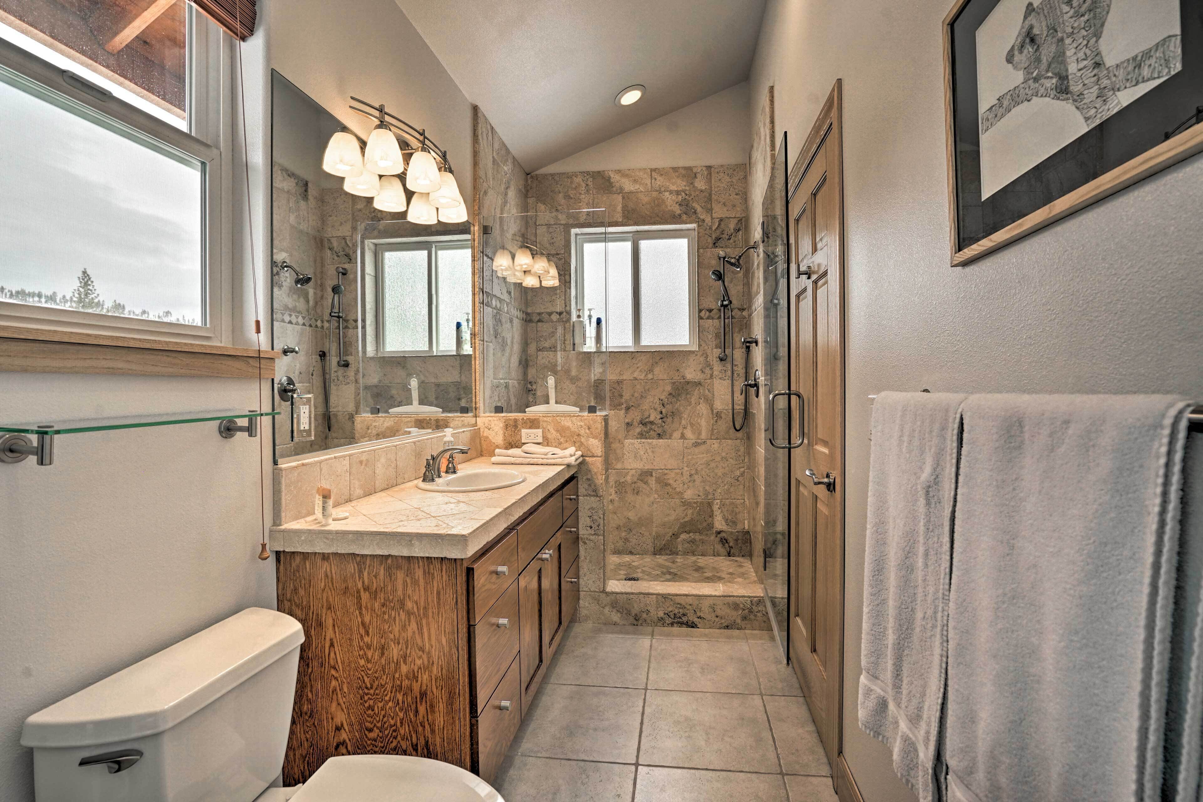 Un baño moderno con ducha de piedra, lavamanos doble y un espejo grande.