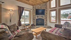 A cozy living room with a stone fireplace, large windows, and a flat-screen TV. - 9 Mi to Heavenly Mountain: South Lake Tahoe Home! (South Lake Tahoe)