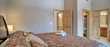 A bedroom with a large bed, a nightstand, a wooden wardrobe, and an open door leading to a bathroom.