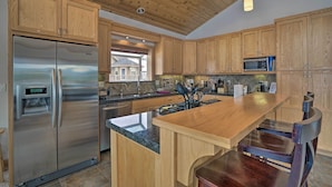 A modern kitchen with wooden cabinets, stainless steel appliances, and a large island with bar seating. - 9 Mi to Heavenly Mountain: South Lake Tahoe Home! (South Lake Tahoe)