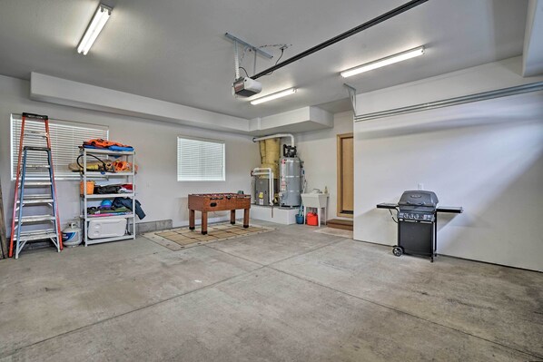 Eine Garage mit Tischfußball, einer Leiter, Regalen voller Werkzeug, einem Warmwasserbereiter und einem Grill.