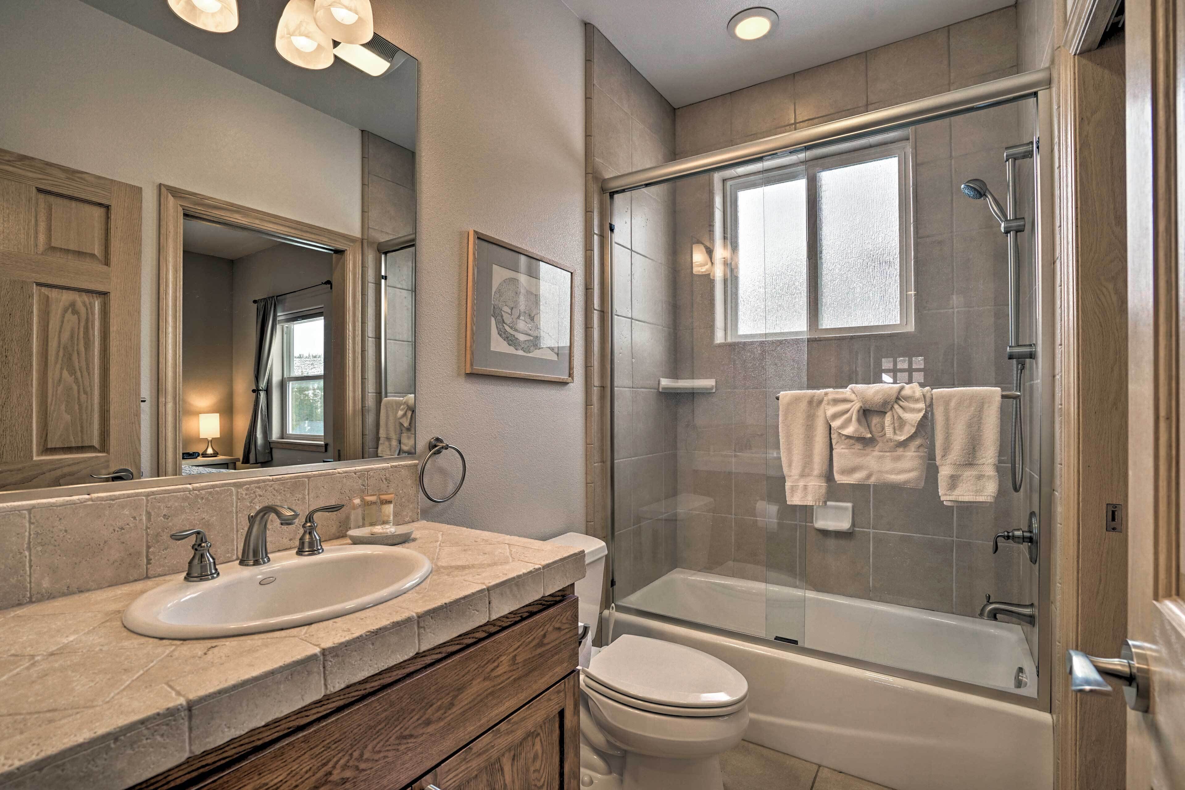 A modern bathroom with a double sink, toilet, and glass-enclosed shower.