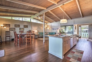 A spacious living area with wooden flooring, a dining table, and a kitchen island. - Oceanfront Kona Home w/ Beach Access & Views! (Kailua-Kona)