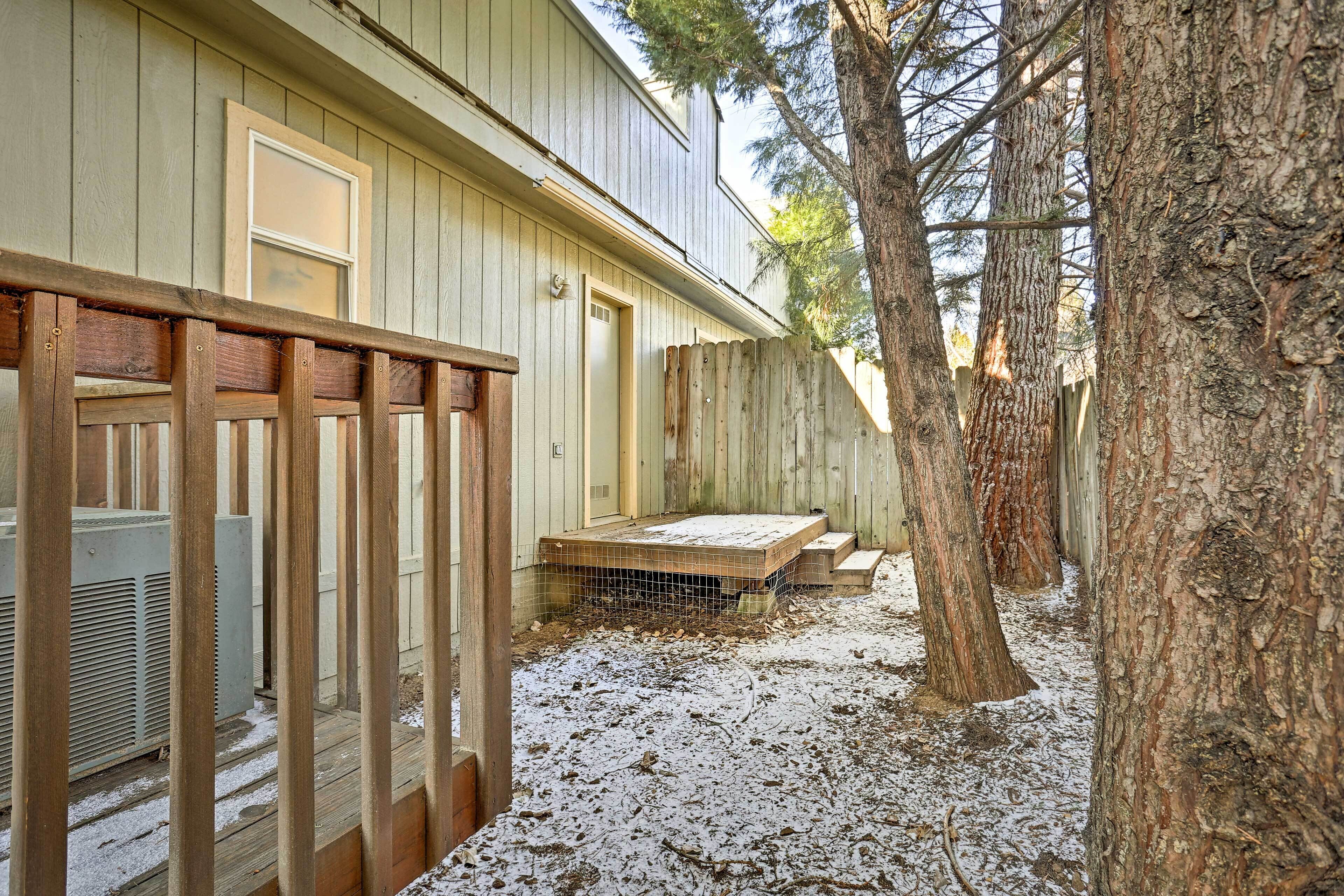A wooden deck with a metal railing, a covered outdoor seating area, and a large tree.