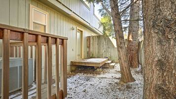 A wooden deck with a metal railing, a covered outdoor seating area, and a large tree.