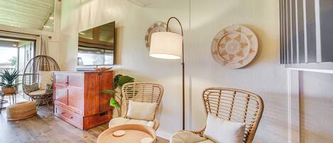 A cozy room with wicker furniture, a wooden cabinet, and a floor lamp.