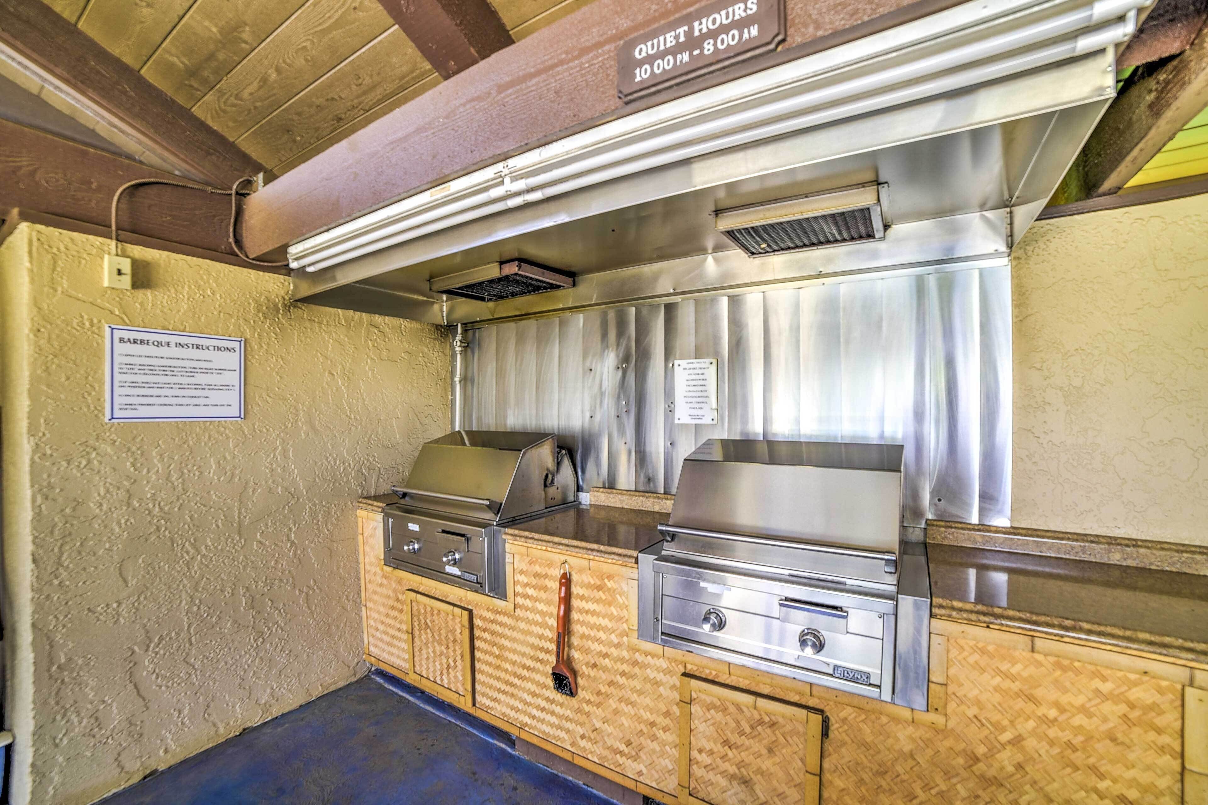 A barbecue area with stainless steel grills and a sign indicating quiet hours from 10:00 PM to 8:00 AM.