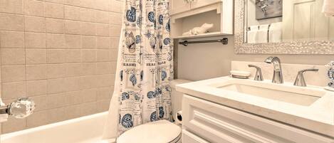 A bathroom with a bathtub, toilet, and vanity with a mirror.