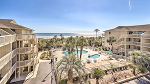 Un hôtel doté d’une piscine, de palmiers et offrant une vue sur la plage.