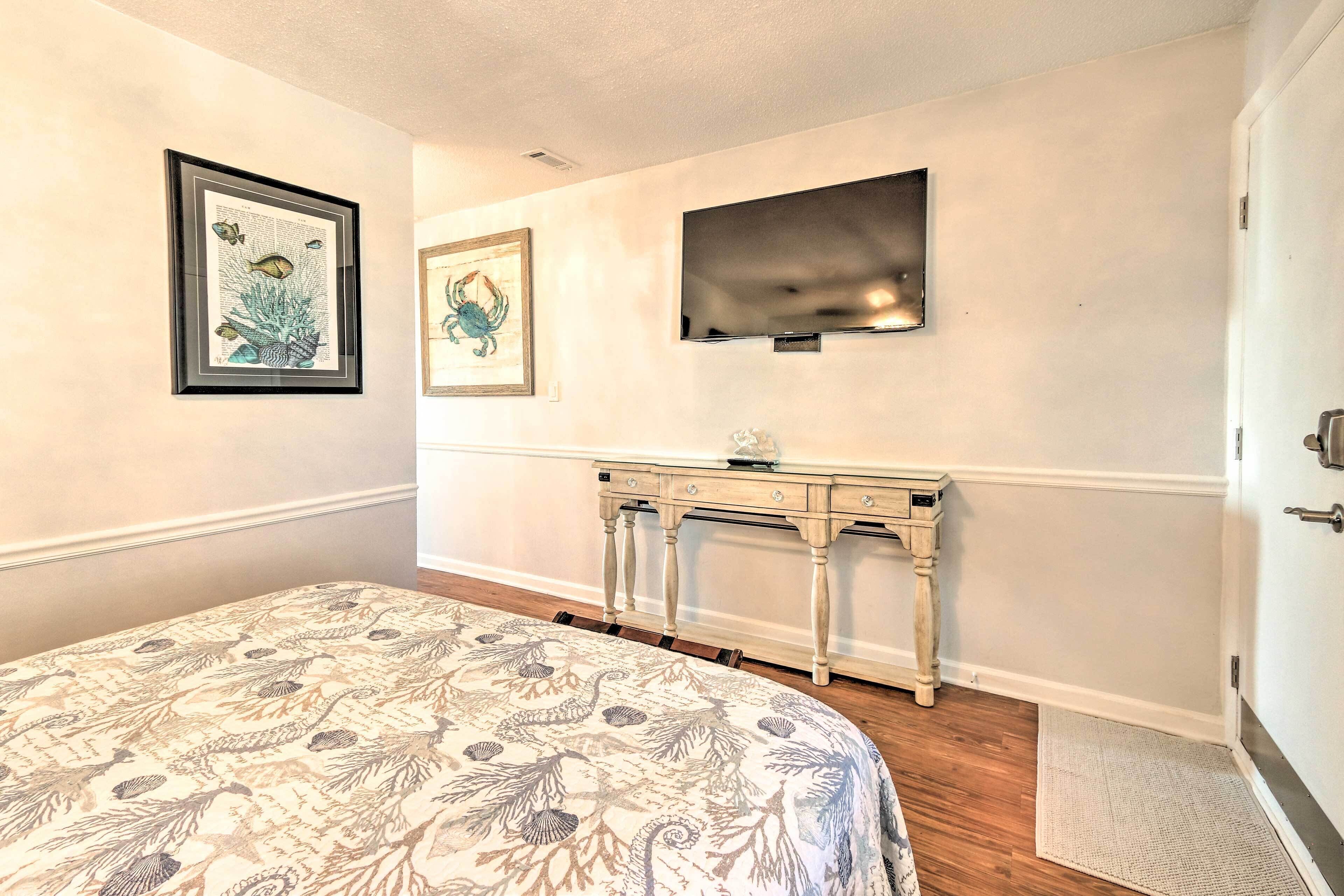 Une chambre à coucher comprenant un lit, une commode, un téléviseur à écran plat et des œuvres d’art encadrées accrochées au mur.