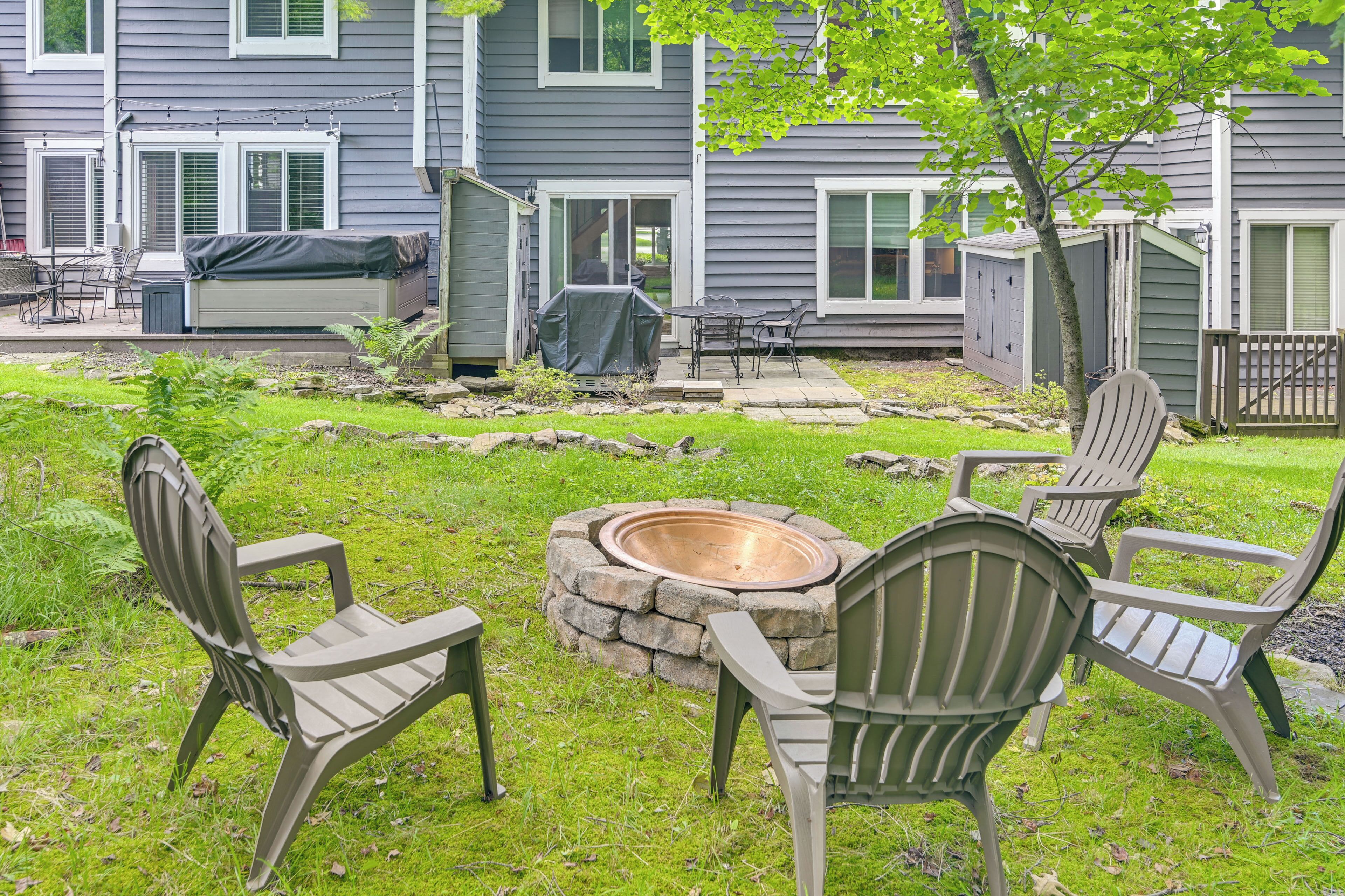 Un jardin avec un foyer, du mobilier d’extérieur et un espace barbecue couvert.