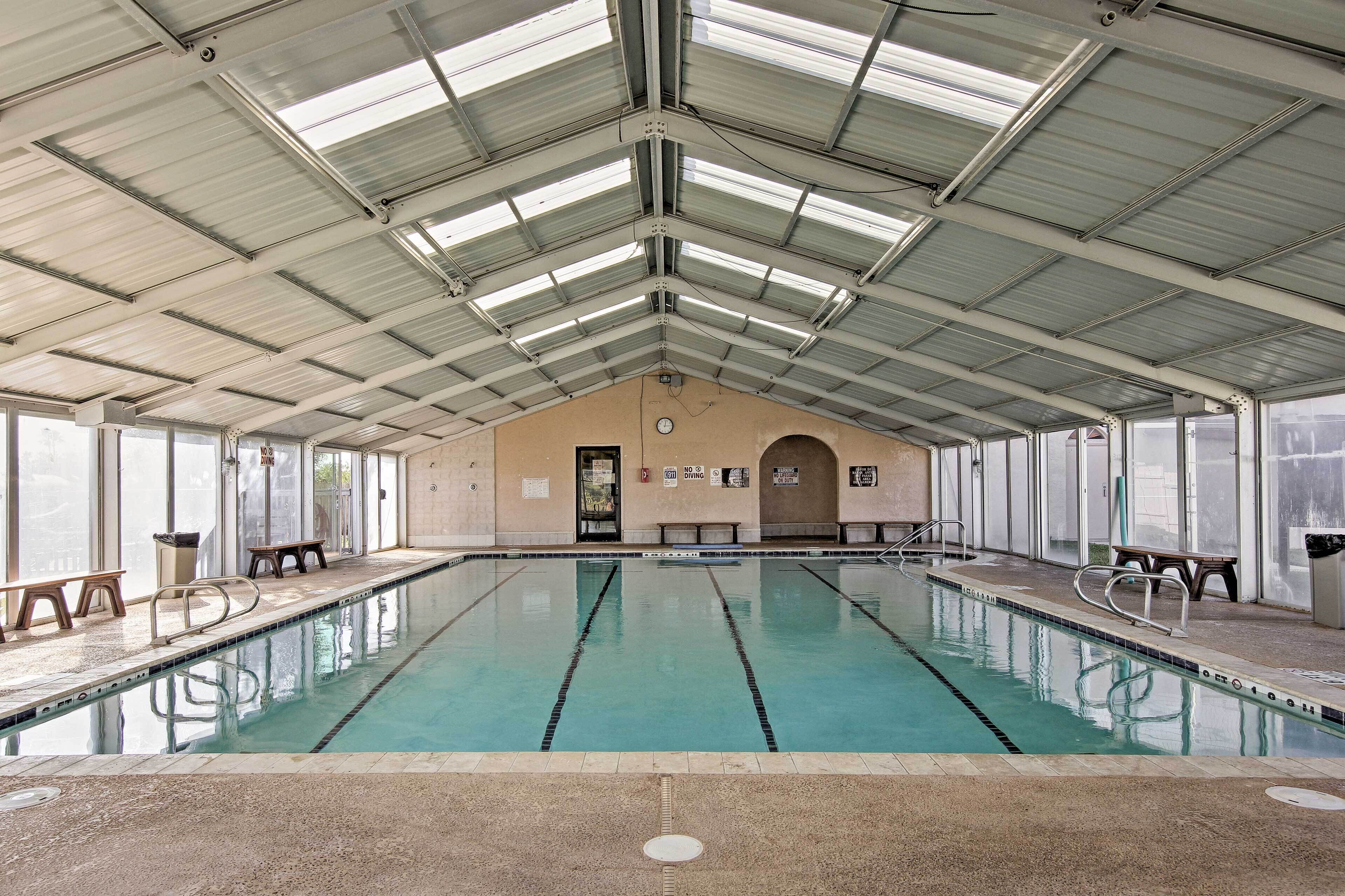 Una piscina interior con carriles delimitados, bancos y un techo alto con tragaluces.