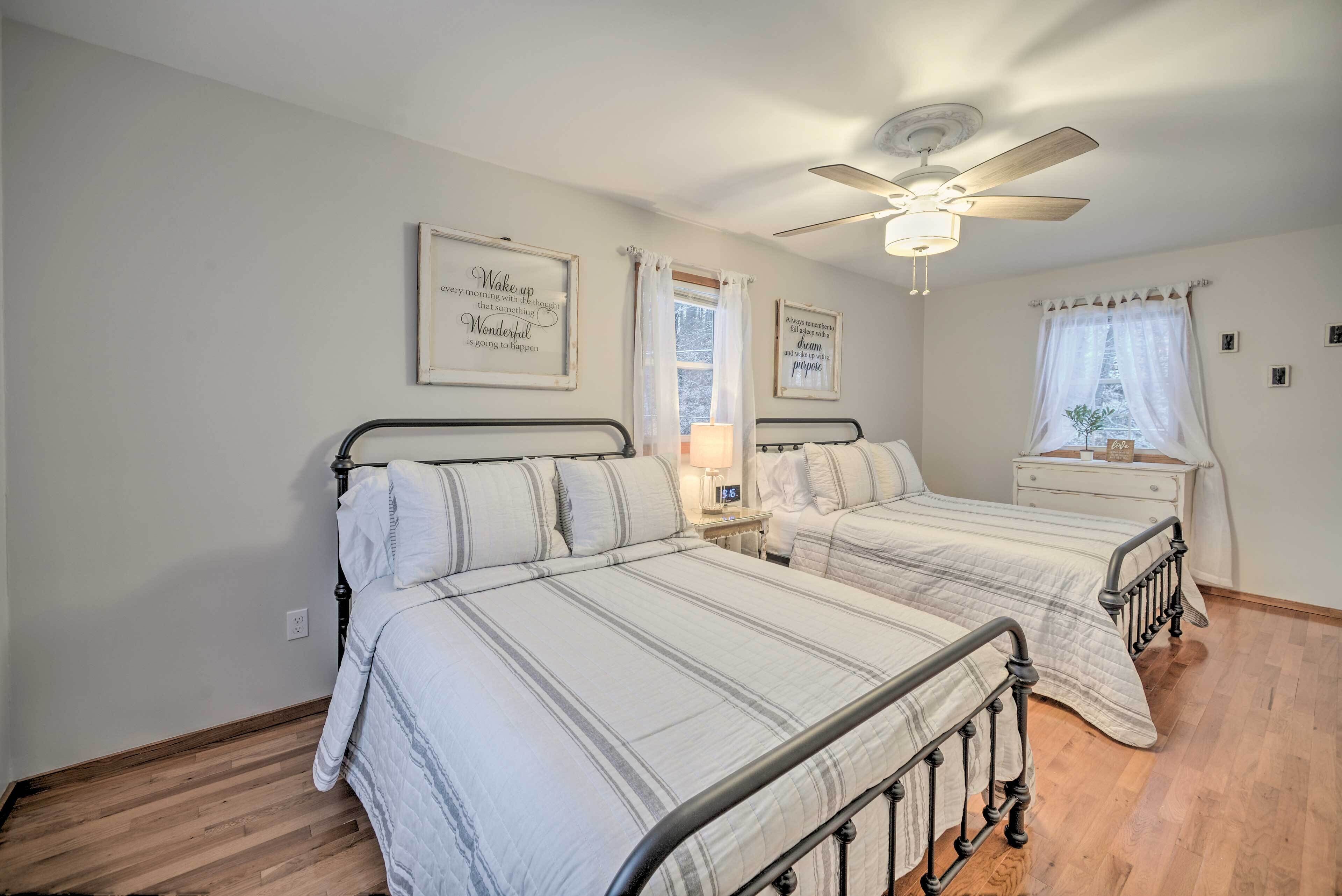 A bedroom with two beds, a ceiling fan, and motivational wall art.
