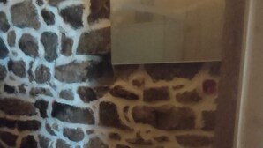 Een badkamer met een stenen muur, een witte wastafel en een spiegel erboven.