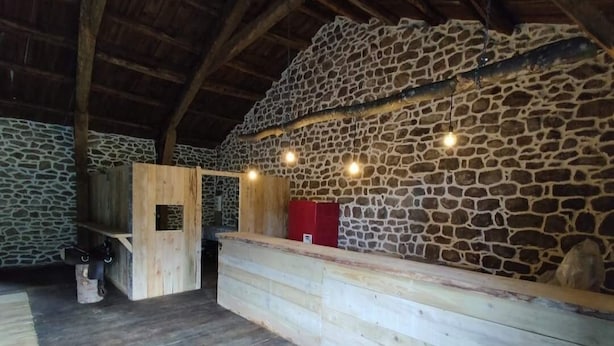 Een rustiek interieur met een stenen muur, een houten bank en een rode kast.