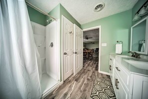 A hallway with a shower, a dining area, and a bathroom with a sink and mirror. - Spacious Geneva House < .5 Mi to The Strip! (Geneva)