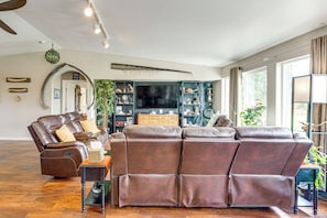 A spacious living room with a brown leather sofa, a wooden coffee table, and a television.