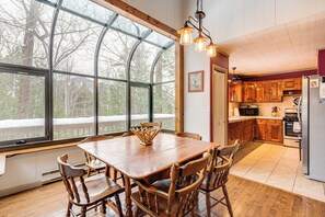 Una cocina amplia con armarios de madera, una mesa de comedor grande y vistas a un paisaje nevado a través de ventanas amplias.