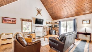 Ein gemütliches Wohnzimmer mit Kamin, Ledersofas, einem Fernseher und Holzböden.