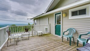 A wooden deck with outdoor furniture, a green door, and a view of the mountains. - Beautiful Winter Escape on Bromley Mountain! (Peru)