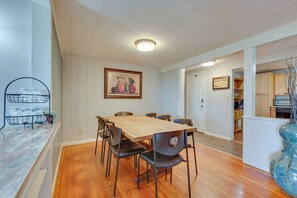 A dining area with a wooden table and chairs, a fruit painting on the wall, and a kitchen in the background. - Beautiful Winter Escape on Bromley Mountain! (Peru)
