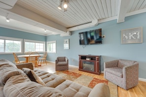 A living room with a large sofa, a patterned armchair, a wooden coffee table, and a television mounted on the wall. - Beautiful Winter Escape on Bromley Mountain! (Peru)