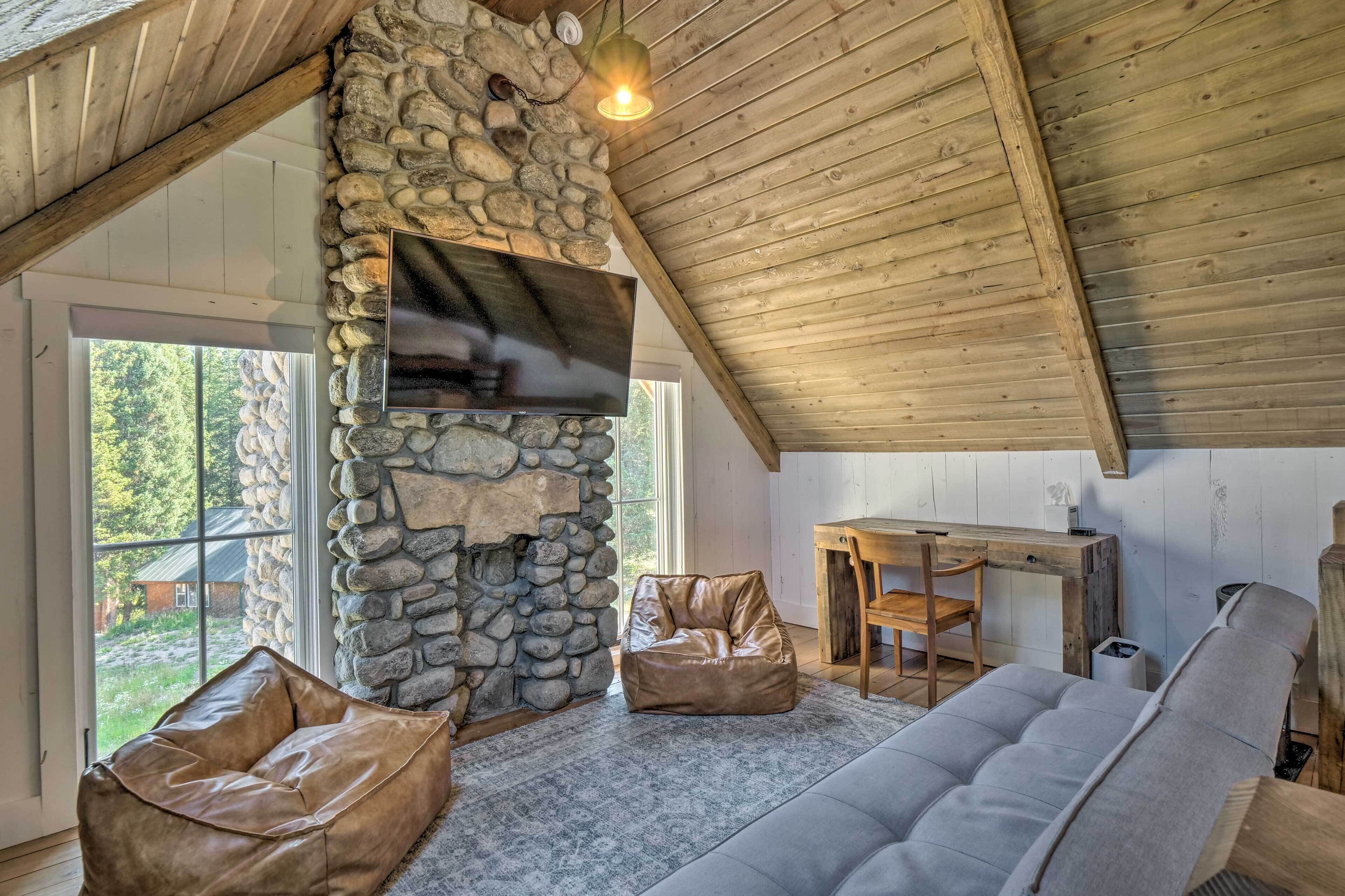 A cozy room with a stone wall, a flat-screen TV, a wooden table, and two bean bags.