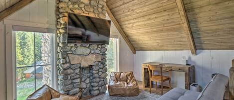 A cozy room with a stone wall, a flat-screen TV, a wooden table, and two bean bags.