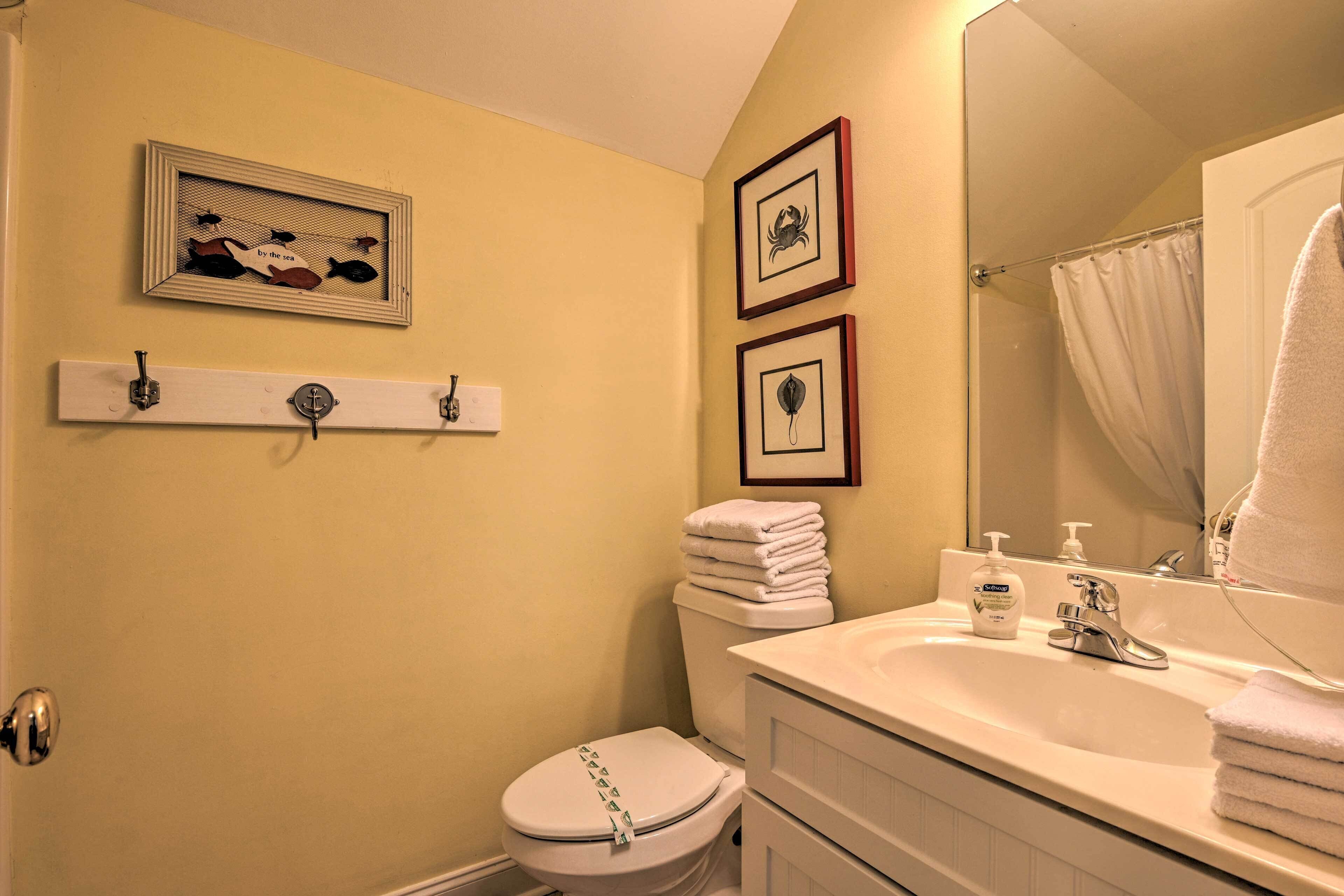 A bathroom with a toilet, sink, and framed pictures on the wall.