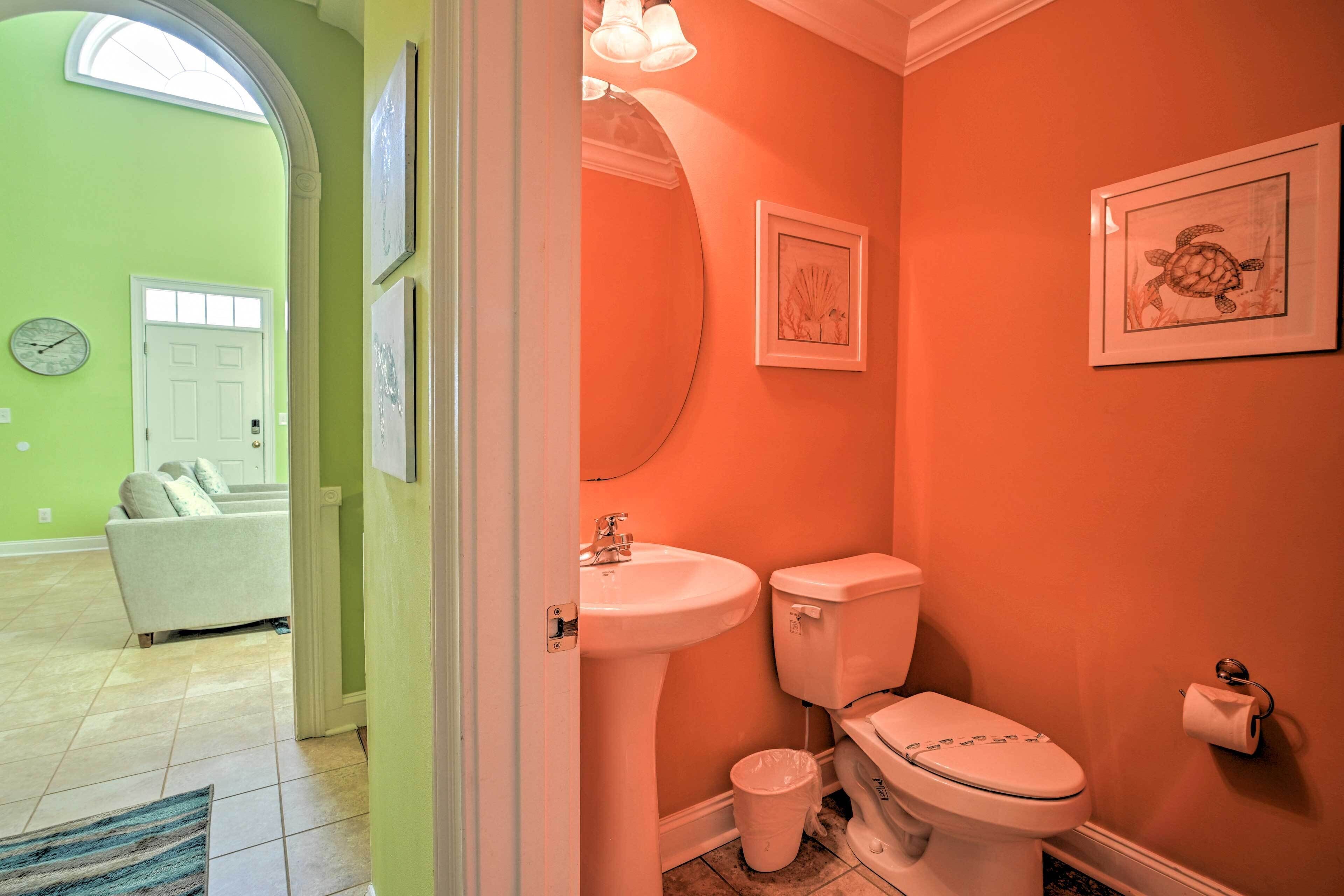 A bathroom with a sink, toilet, and framed artwork on the wall.