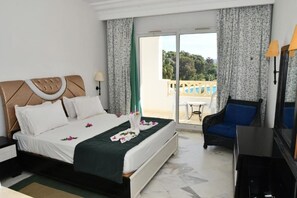 A hotel room with a bed, a chair, a TV, and a balcony with a view. - Prestige Resort Hammamet (Hammamet)