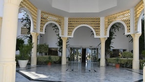 A spacious courtyard with marble flooring, white columns, and decorative arches.