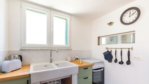 A kitchen with a double sink, a toaster, a stove, and a clock on the wall. - Viewsuvio Terrace at historical center (Napoli)