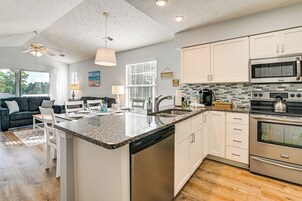 Una cocina moderna con armarios blancos, encimera de granito, electrodomésticos de acero inoxidable y lavavajillas.