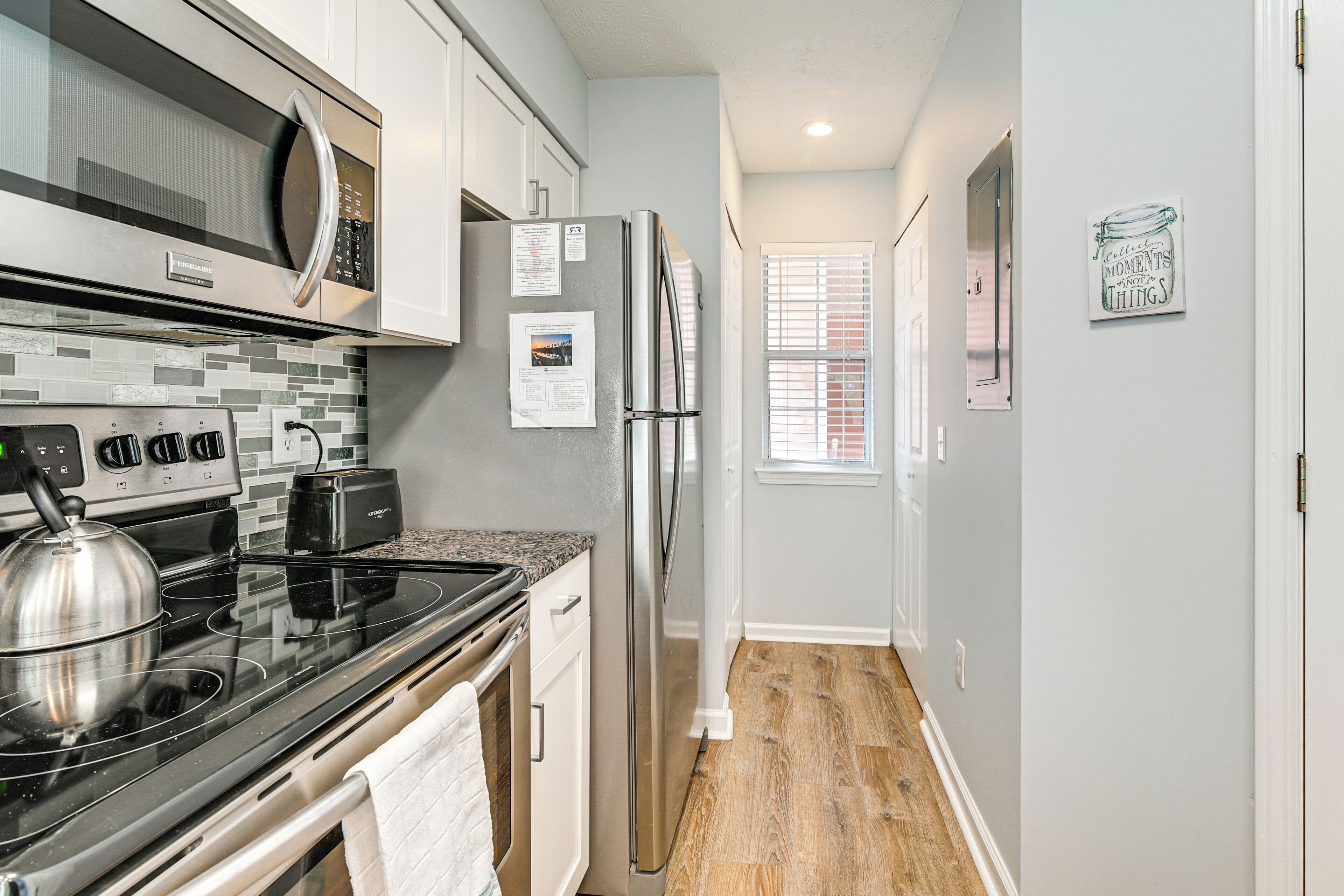 A modern kitchen with stainless steel appliances, a black stovetop, and a tiled backsplash.