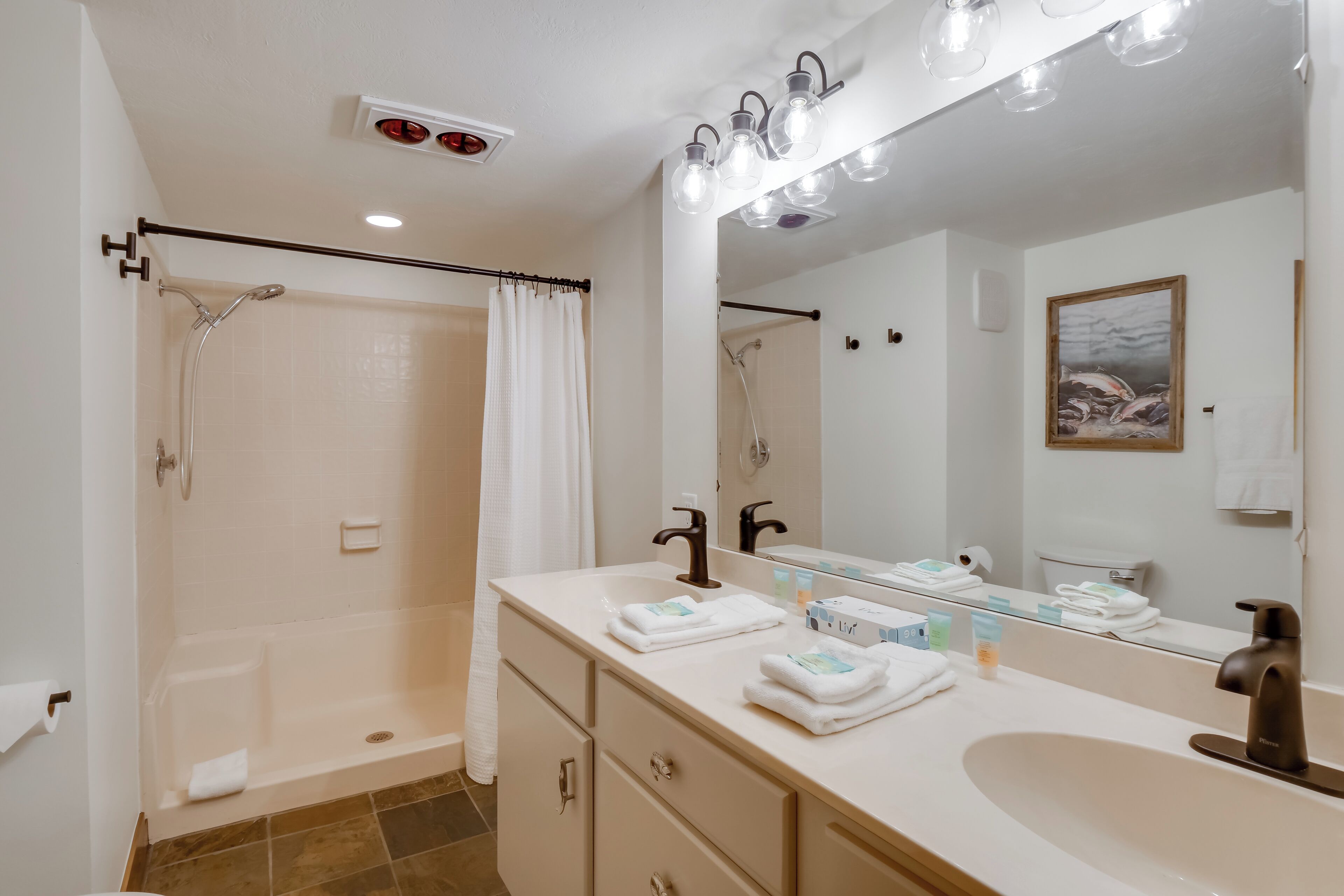 A modern bathroom with a walk-in shower, a large mirror, and a vanity with a sink and multiple drawers.