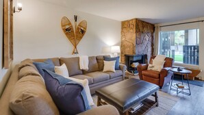 A cozy living room with a stone fireplace, a sofa set, a coffee table, and a chair with a cushion. - Walk to Ski Shuttle: Cozy Mountain Meadows Condo (Frisco)