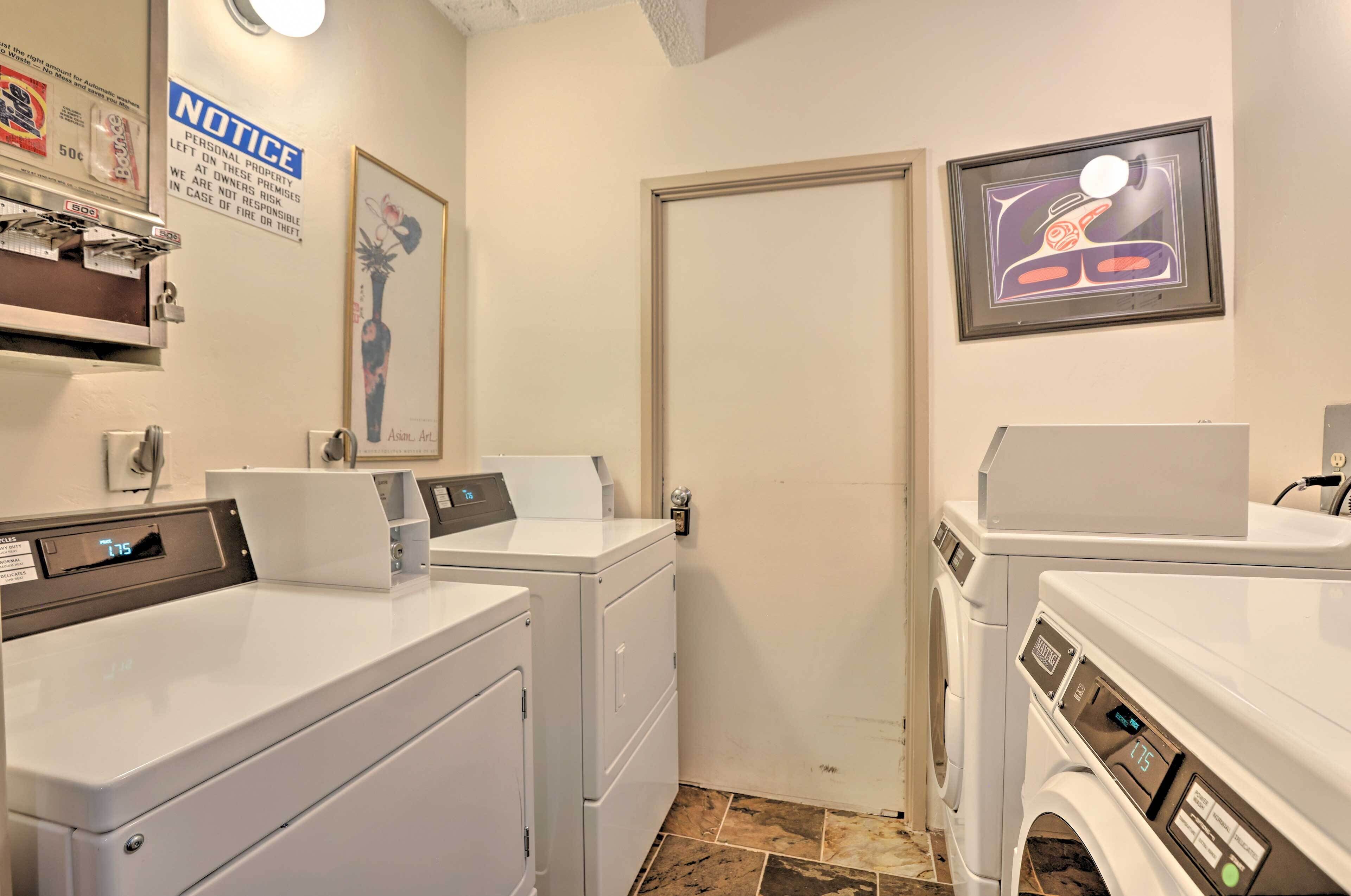A laundry room with multiple washing machines, a notice on the wall, and a door.