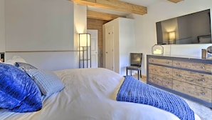 Une chambre à coucher avec un lit, une commode, une chaise et un miroir.