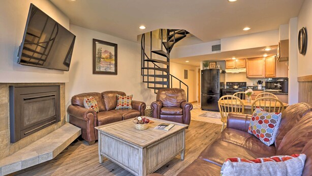 Un salon moderne avec des canapés en cuir, une table basse en bois, une cheminée et une cuisine en arrière-plan.