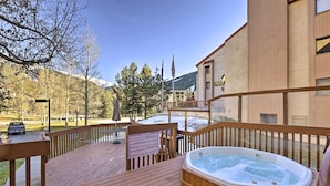 Une terrasse en bois avec un jacuzzi, un panneau indicateur et une vue sur une montagne et des arbres.