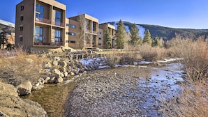 Un bâtiment moderne doté de nombreux balcons donnant sur un ruisseau aux rives rocheuses.